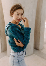 [Color: Teal/Blue] Beautiful model wearing a teal blue and green hooded pullover sweater with drawstring details. Super cute and soft hoodie paired with light wash denim and Ray Ban sunglasses.