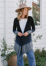 [Color: Navy/Grey] A model wearing a navy blue and grey dip dyed cardigan sweater. A lightweight bohemian cardigan with an adjustable drawstring hemline, long sleeves, and an open front. 