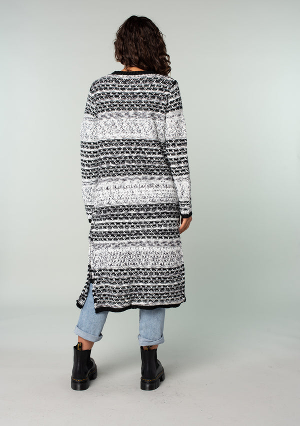 [Color: Black/Grey] A back facing image of a brunette model wearing a black and grey mixed knit long duster cardigan.