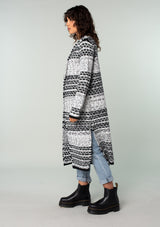 [Color: Black/Grey] A side facing image of a brunette model wearing a black and grey mixed knit long duster cardigan.