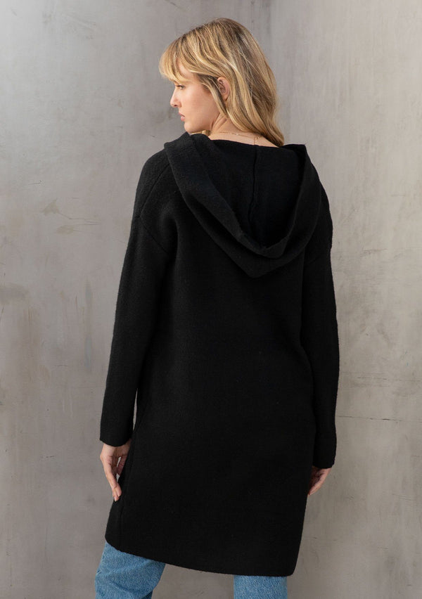 [Color: Black] A classic and essential hooded black coatigan. A cozy and effortlessly chic cardigan coat, featuring essential side pockets, a cozy oversized hood, and a contrast white shell button up front. 