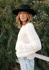 [Color: Winter White] A model wearing a white chunky open knit sweater. With long voluminous balloon sleeves and a crew neckline. 