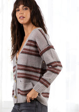 [Color: Grey/Raisin] A model wearing a grey stripe cardigan sweater. With three oversize buttons, front pockets, and a v neckline.