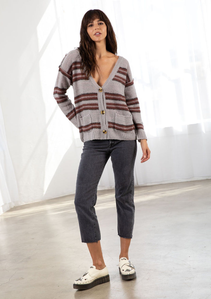 [Color: Grey/Raisin] A model wearing a grey stripe cardigan sweater. With three oversize buttons, front pockets, and a v neckline.