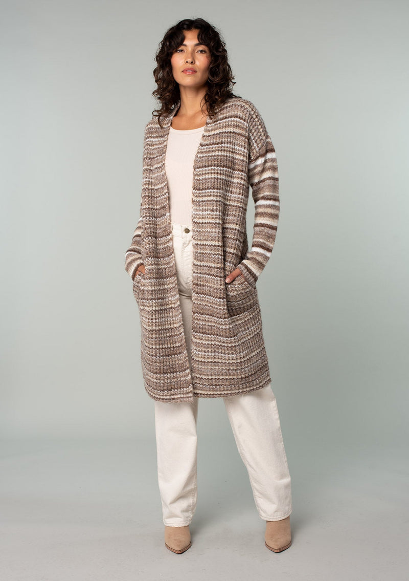 [Color: Brown/Taupe] A full body front facing image of a brunette model wearing a white and brown striped long cardigan. With an open front, contrast striped long sleeves, a shawl collar, and side pockets. 
