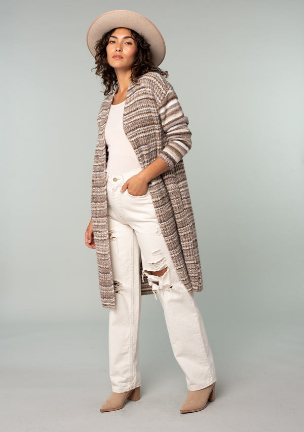 [Color: Brown/Taupe] A front facing image of a brunette model wearing a white and brown striped long cardigan. With an open front, contrast striped long sleeves, a shawl collar, and side pockets. 