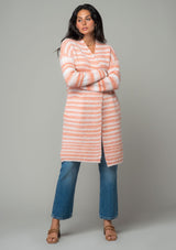 [Color: Ivory/Peach] A front facing image of a brunette model wearing a white and peach striped long cardigan. With an open front, contrast striped long sleeves, a shawl collar, and side pockets. 
