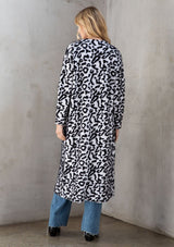 [Color: Snow Leopard] Ultra soft and fuzzy statement cardigan in a bold allover snow leopard print. A duster length sweater featuring oversize front patch pockets. Styled here with a black mini dress and boots.