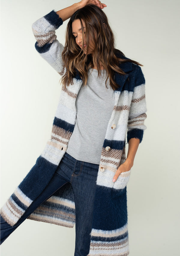[Color: Ivory/Navy] A front facing image of a brunette model wearing a soft sweater coat in a blue and ivory stripe. With a button front, long sleeves, side patch pockets, and a notched lapel. 