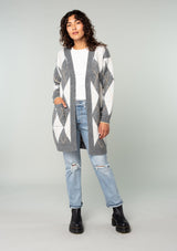[Color: Charcoal/Grey] A front facing image of a brunette model wearing an ultra soft mid length cardigan in a grey and light grey argyle plaid pattern. With long sleeves, an open front, and side pockets. 
