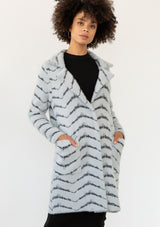 [Color: Grey/Charcoal] A model wearing a soft and fuzzy sweater coat in a grey and charcoal chevron design. With a snap button front, side pockets, and a classic notched lapel. 
