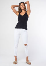[Color: Black] A model wearing a black slim fit knit sweater tank top with adjustable straps and a v neckline.
