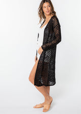 [Color: Black] A model wearing a classic bohemian black mid length crochet cardigan.