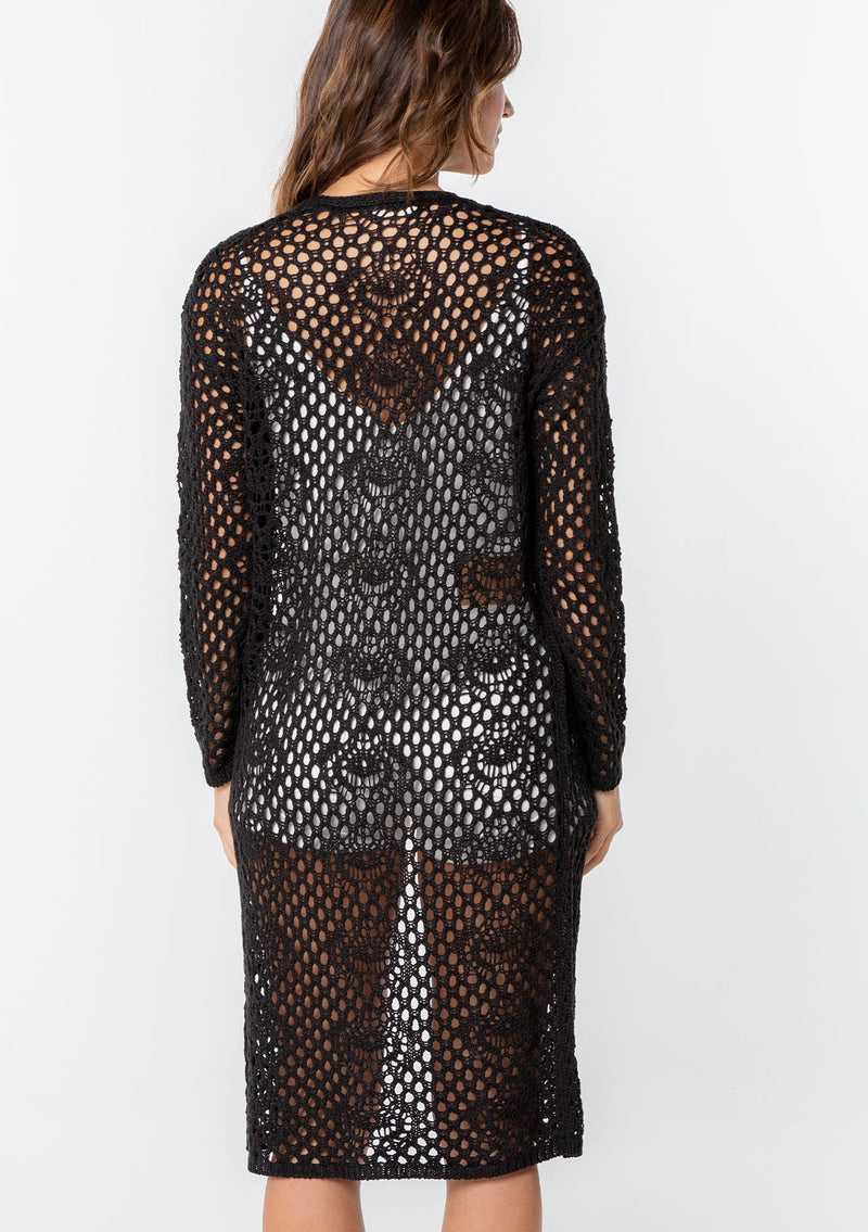 [Color: Black] A model wearing a classic bohemian black mid length crochet cardigan.