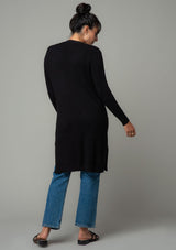 [Color: Black] A back facing image of a brunette model wearing a black waffle knit cardigan. A lightweight mid length cardigan sweater with long sleeves, side pockets, and an open front. 