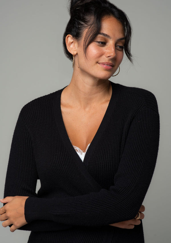 [Color: Black] A close up front facing image of a brunette model wearing a black waffle knit cardigan. A lightweight mid length cardigan sweater with long sleeves, side pockets, and an open front. 