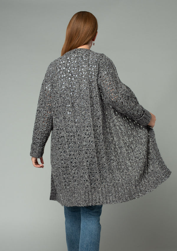 [Color: Charcoal] A back facing image of a red headed model wearing a dark charcoal grey open knit cardigan sweater. A mid length lightweight cardigan with long sleeves, an open front, and ribbed wrist cuffs. 