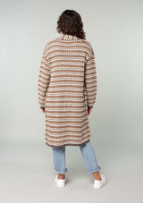 [Color: Mocha Multi] A back facing image of a brunette model wearing a brown multi color stripe chunky knit fall cardigan. A long duster cardigan with an open front, long sleeves, and side pockets with contrast trim. 