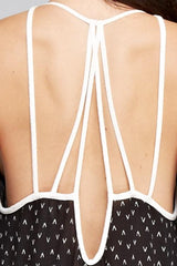 [Color: Black/Vanilla] A detail image of a brunette woman wearing a printed black v neck maxi dress with a strappy back.