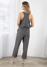 [Color: Ash Wash] A blond model wearing a classic jumpsuit made from eco friendly Tencel. Featuring a wide leg with a cuffed hem, essential side pockets, and a button front.