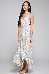 [Color: Natural Multi] A brunette model wearing a boho striped geo print halter maxi dress with a flowy shark bite skirt, open back, and a flattering v-neckline. 