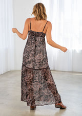 [Color: Black/Mocha] A back facing image of a blonde model wearing a brow and black printed chiffon maxi dress with a scoop neckline and spaghetti straps. 