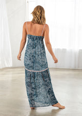 [Color: Navy/Blue] A back facing image of a blonde model wearing a blue printed chiffon maxi dress with a scoop neckline and spaghetti straps. 