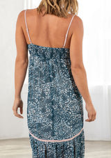 [Color: Navy/Blue] A back facing image of a blonde model wearing a blue printed chiffon maxi dress with a scoop neckline and spaghetti straps. 