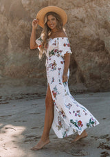 [Color: Vanilla Combo] A woman on the beach wearing an off shoulder floral print maxi dress. Featuring a front slit, short flutter sleeves, and a tie halter neck that can be tied multiple ways.