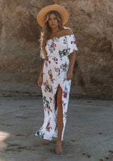 [Color: Vanilla Combo] A woman on the beach wearing an off shoulder floral print maxi dress. Featuring a front slit, short flutter sleeves, and a tie halter neck that can be tied multiple ways.