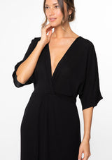 [Color: Black] A model wearing a black maxi dress with a knot front detail and half length kimono sleeves.  