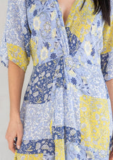 [Color: Blue/Lime] A model wearing a blue and lime green floral patchwork maxi dress with short kimono sleeves and a twist front detail. 