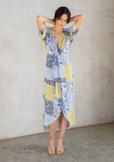 [Color: Blue/Lime] A model wearing a blue and lime green floral patchwork maxi dress with short kimono sleeves and a twist front detail. 