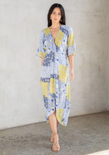 [Color: Blue/Lime] A model wearing a blue and lime green floral patchwork maxi dress with short kimono sleeves and a twist front detail. 