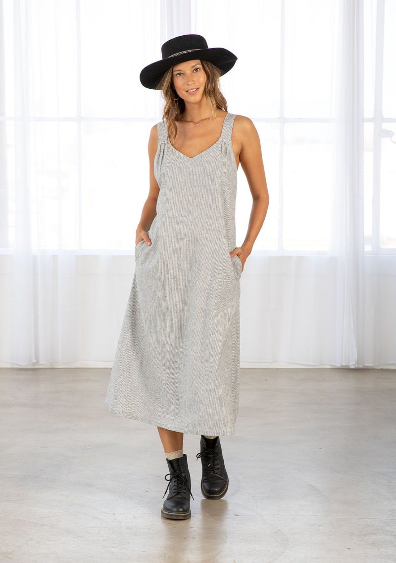 [Color: Navy/White] A model wearing a linen and cotton blend, navy and white stripe mid length dress. With thick tank top straps, a low back, side pockets, and an oversize silhouette. 