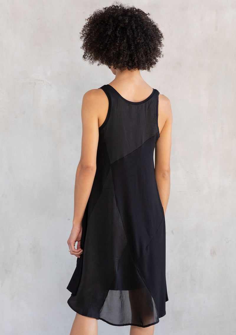[Color: Black] A model wearing a sleeveless mini dress designed in a woven and knit mixed media patchwork. With a scooped neckline and attached lining.
