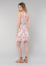 [Color: Natural/Rose] A back facing image of a blonde model wearing a bohemian spring mini dress in a rose pink floral print. With spaghetti straps, a split v neckline with tassel ties, a smocked elastic waist, and a flowy tiered skirt.