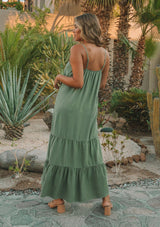 [Color: Olive] A model wearing a classic sleeveless olive green maxi dress. With a v neckline, adjustable spaghetti straps, and a tiered skirt for movement.