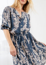 [Color: Denim/Ivory] A blond model wearing a floral print button front mini dress. With half length sleeves, an elastic flounce cuff, and an elastic drawstring waist.