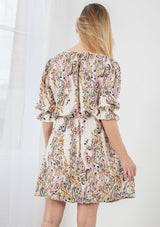 [Color: Ivory/Coral] A blond model wearing a floral print button front mini dress. With half length sleeves, an elastic flounce cuff, and an elastic drawstring waist.