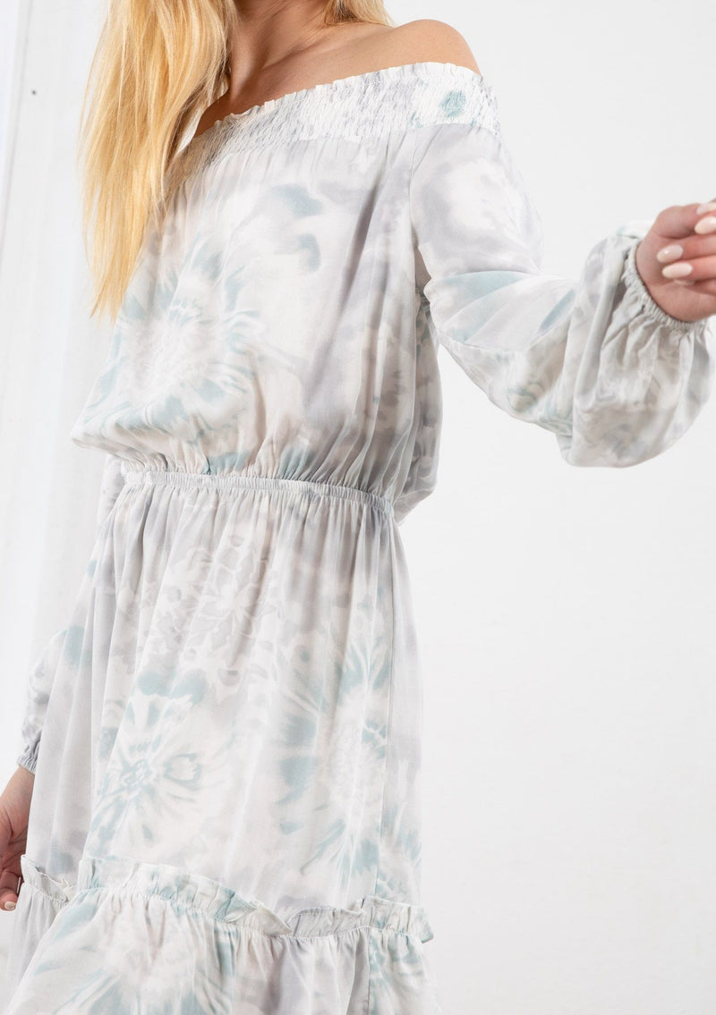 [Color: Lavender/Grey] A blond model wearing a tie dye mini dress. Featuring a smocked off the shoulder detail, an elastic waist, voluminous long sleeves, and a tiered ruffle trimmed skirt. 