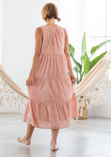 [Color: Blush] A woman wearing a lightweight sleeveless cotton voile maxi dress. Featuring pretty embroidered details throughout, a split v neckline with tassel ties, and a flattering tent style silhouette with a tiered skirt.
