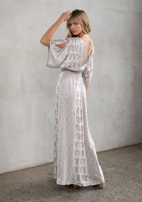 [Color: Natural/Taupe] A model wearing a soft and silky mixed floral print maxi dress. With half length kimono sleeves, a smocked elastic waist, a deep v neckline, and an open back with tassel tie closure.