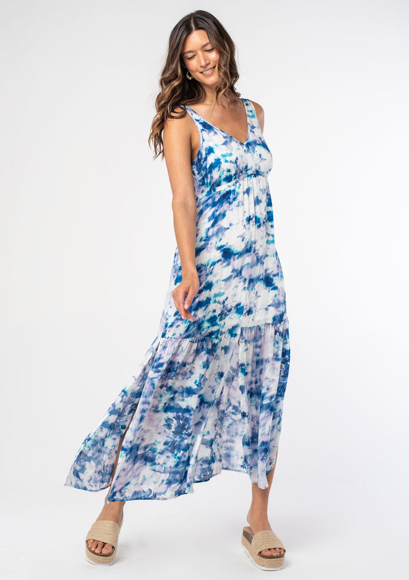 [Color: Navy/Teal] A woman wearing a flowy blue and white floral print bohemian maxi dress with wide tank top straps and a waist tie belt. 