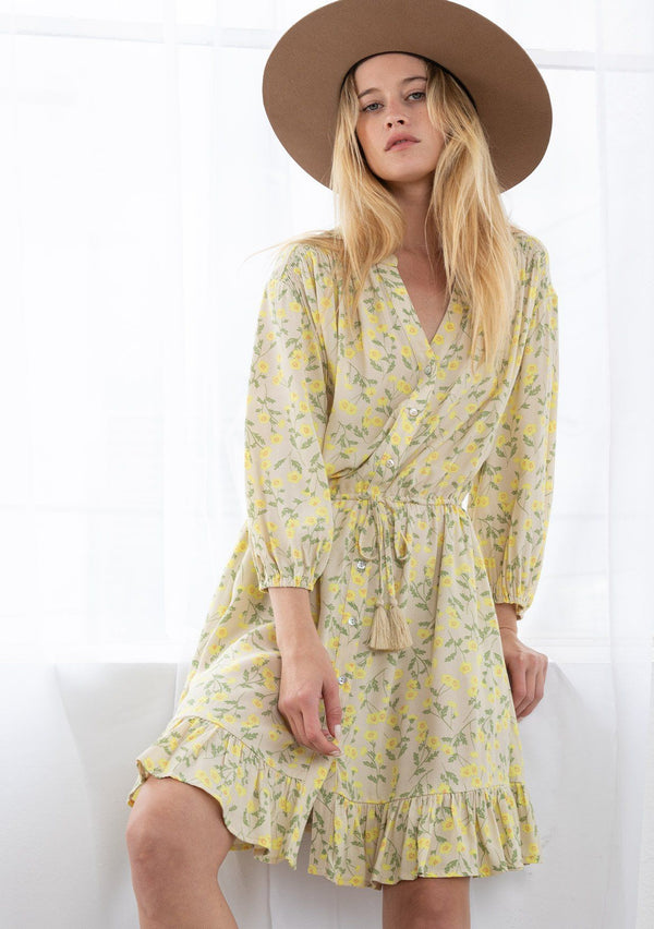 [Color: Natural/Yellow] A blond model wearing a button front mini dress in a small floral print. Featuring long voluminous sleeves, an adjustable tassel tie drawstring waist, and a flounce trimmed skirt. 