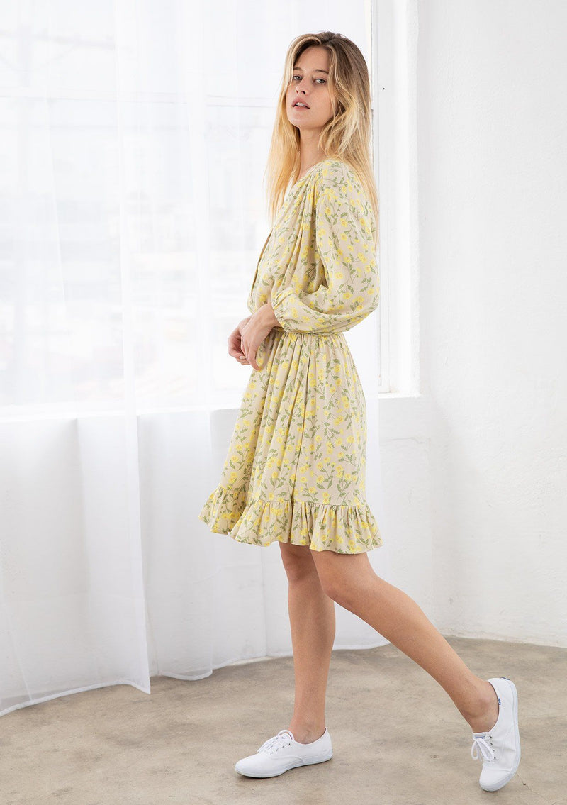 [Color: Natural/Yellow] A blond model wearing a button front mini dress in a small floral print. Featuring long voluminous sleeves, an adjustable tassel tie drawstring waist, and a flounce trimmed skirt. 