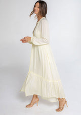 [Color: Lemondrop] A model wearing a timeless yellow maxi peasant dress with a button front, ruffled neckline, long voluminous sleeves, and tiered skirt.