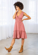 [Color: Terracotta] A model wearing a pink gauze sleeveless mini dress. With embroidered eyelet detail along the waist and shoulder, and elastic waist, and a tiered high low skirt. 