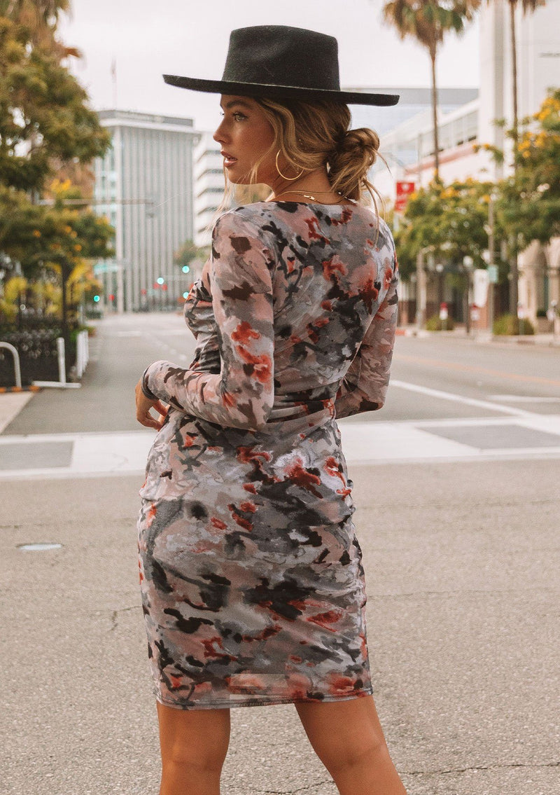 [Color: Slate/Rust] A model wearing a micro mesh mini dress in a camouflage print. With long sleeves, a round neckline, and a slim bodycon fit.
