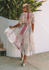 [Color: Natural/Wine] A model wearing a sheer chiffon maxi dress in a pink mixed print. With short dolman sleeves, a button front, an elastic waist, and a v neckline. 